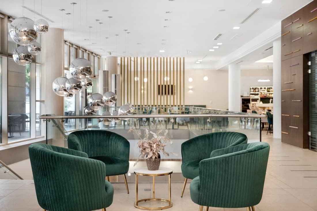 A Corso Hotel Pécs világos, modern társalgója zöld fotelekkel